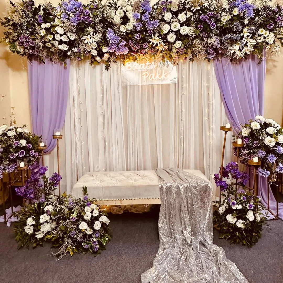 Lilac and white draping beneath a floral canopy with a white bench