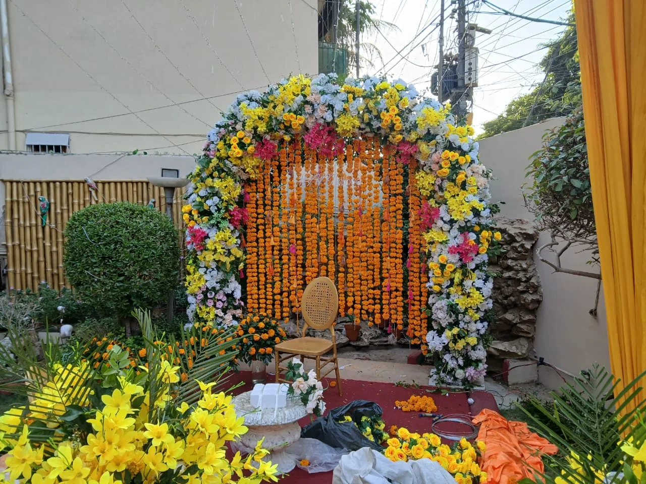 Outdoor floral arch with yellow and orange strands and a central chair
