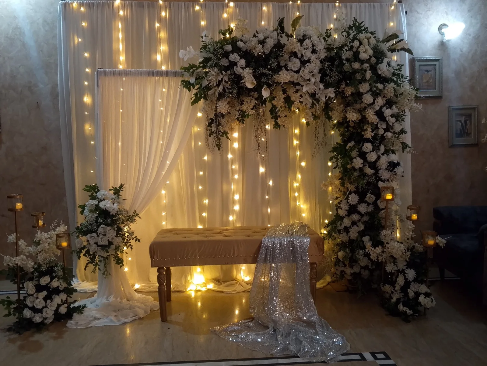 White floral arch and warm string lights behind a decorated table