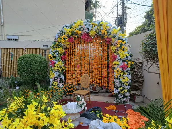 Outdoor floral arch with yellow and orange strands and a central chair
