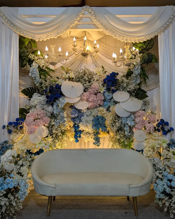 Pastel flowers and white draping framing a curved light-coloured sofa