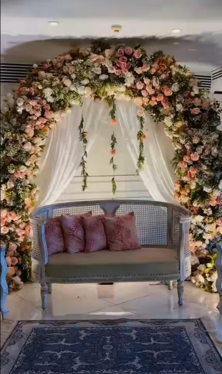 Pink and white floral arch around a grey sofa with mauve cushions