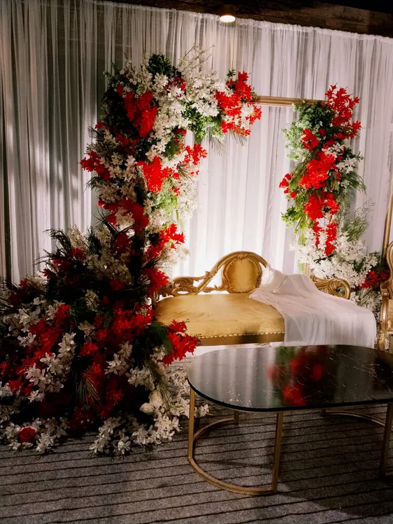 Red and white flowers beside white draping and a gold-coloured event seat
