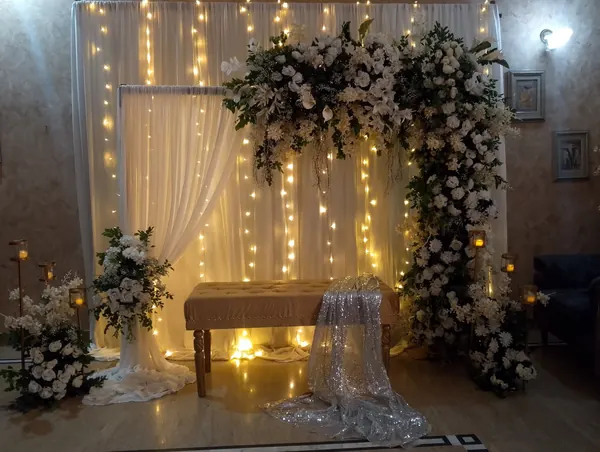 White floral arch and warm string lights behind a decorated table